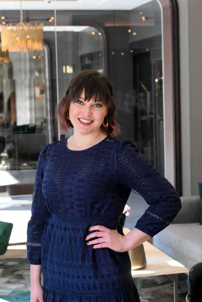Brittany Choate, Director of Programs Saliva Direct Inc. standing wearing a dark blue dress with her hand on her hip.