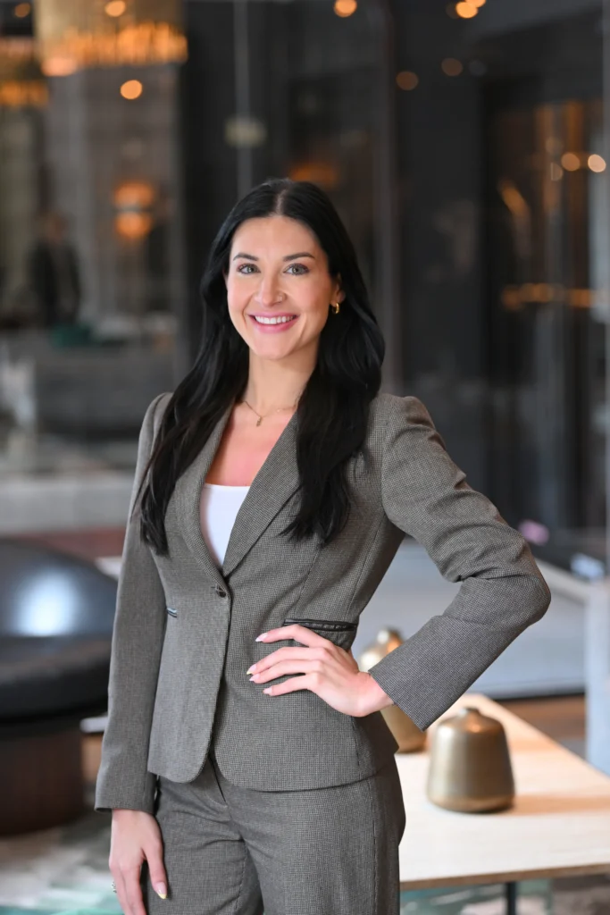 Victoria Hurley, Marketing Manager Saliva Direct Inc. standing wearing a gray suit and white shirt, with her hand on her hip.
