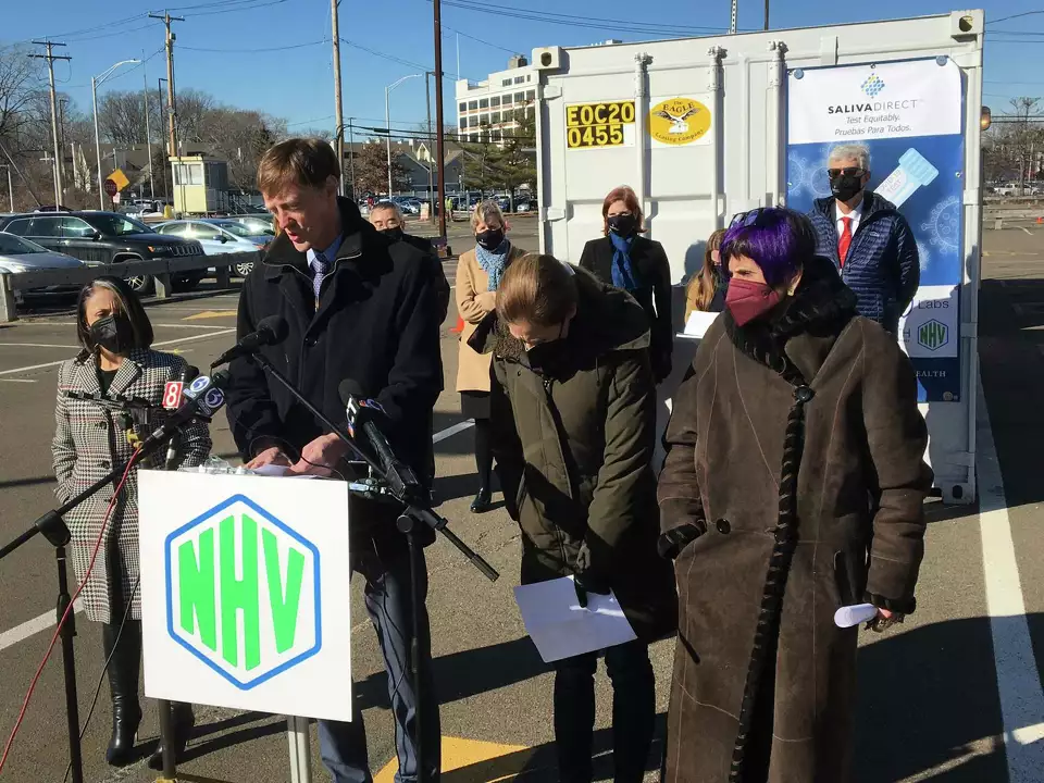 New Haven Connecticut mayor Justin Elicker speaking at an announcement of the new testing partnership between the state of Connecticut Department of Public Health and the SalivaDirect Initiative of the Yale School of Public Health. Six women and two men are standing behind him.