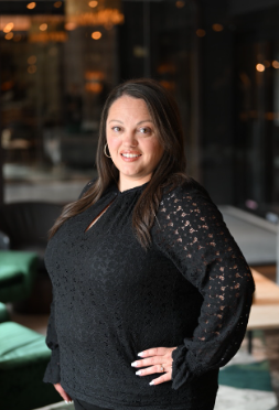 Laura Burke, Regulatory Compliance Manager Saliva Direct Inc. standing wearing a black dress with her hand on her hip.